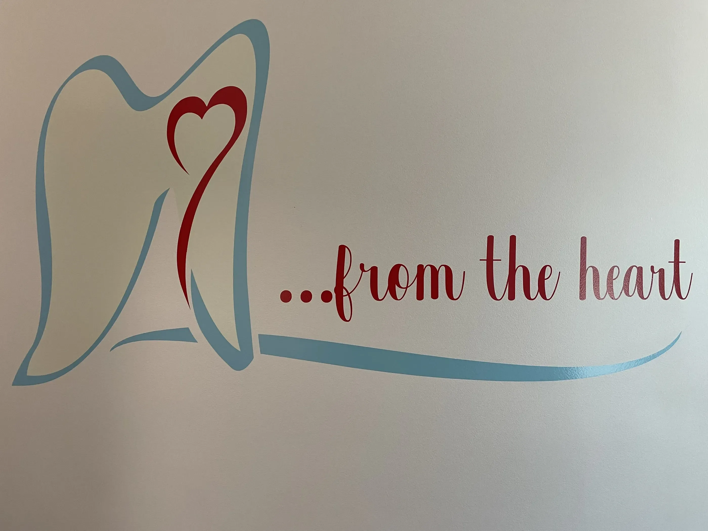 Wall graphic in a dental office featuring a stylized tooth design with a heart and the phrase ‘…from the heart’ in red and blue colors.