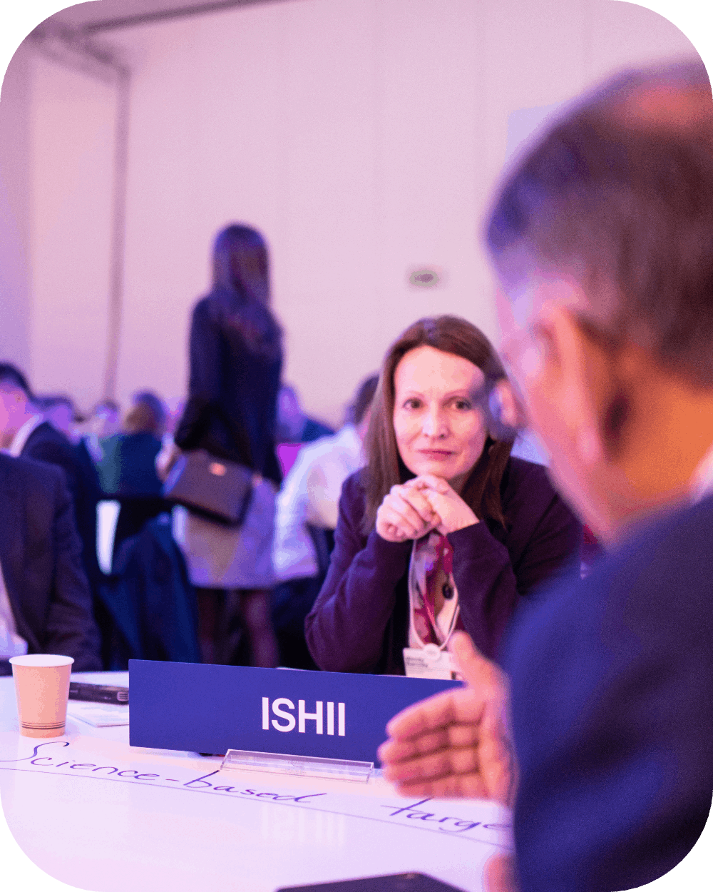 Two people sitting at a table, one of them is listening to the other speak.
