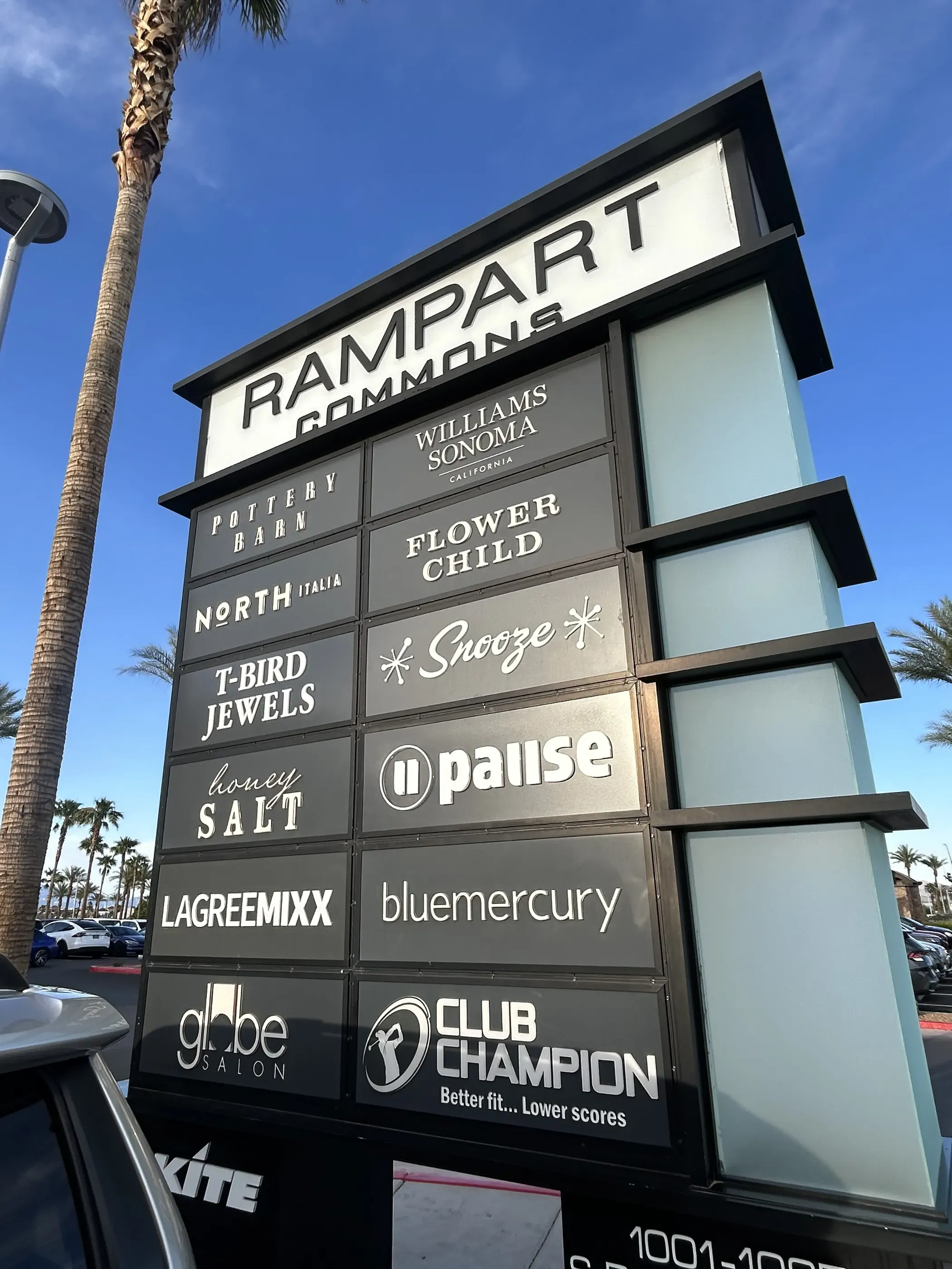 Outdoor shopping center directory sign for Rampart Commons displaying multiple store names.