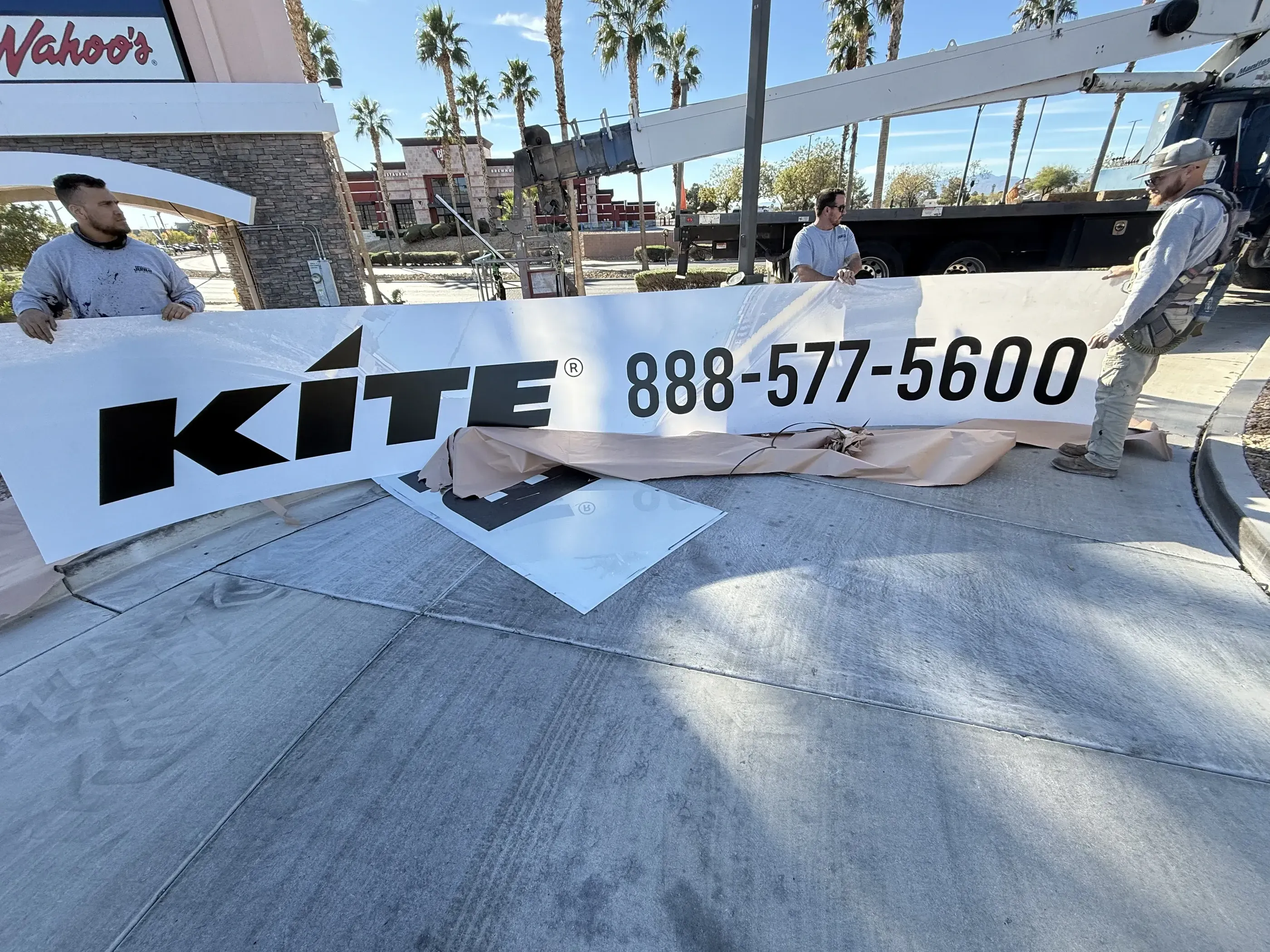 Men holding a completed polycarbonate tenant panels on commercial pylon sign