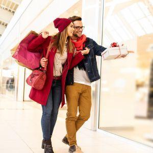 Holiday shoppers pointing toward a business window