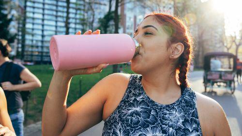 Woman drinking from metal water bottle