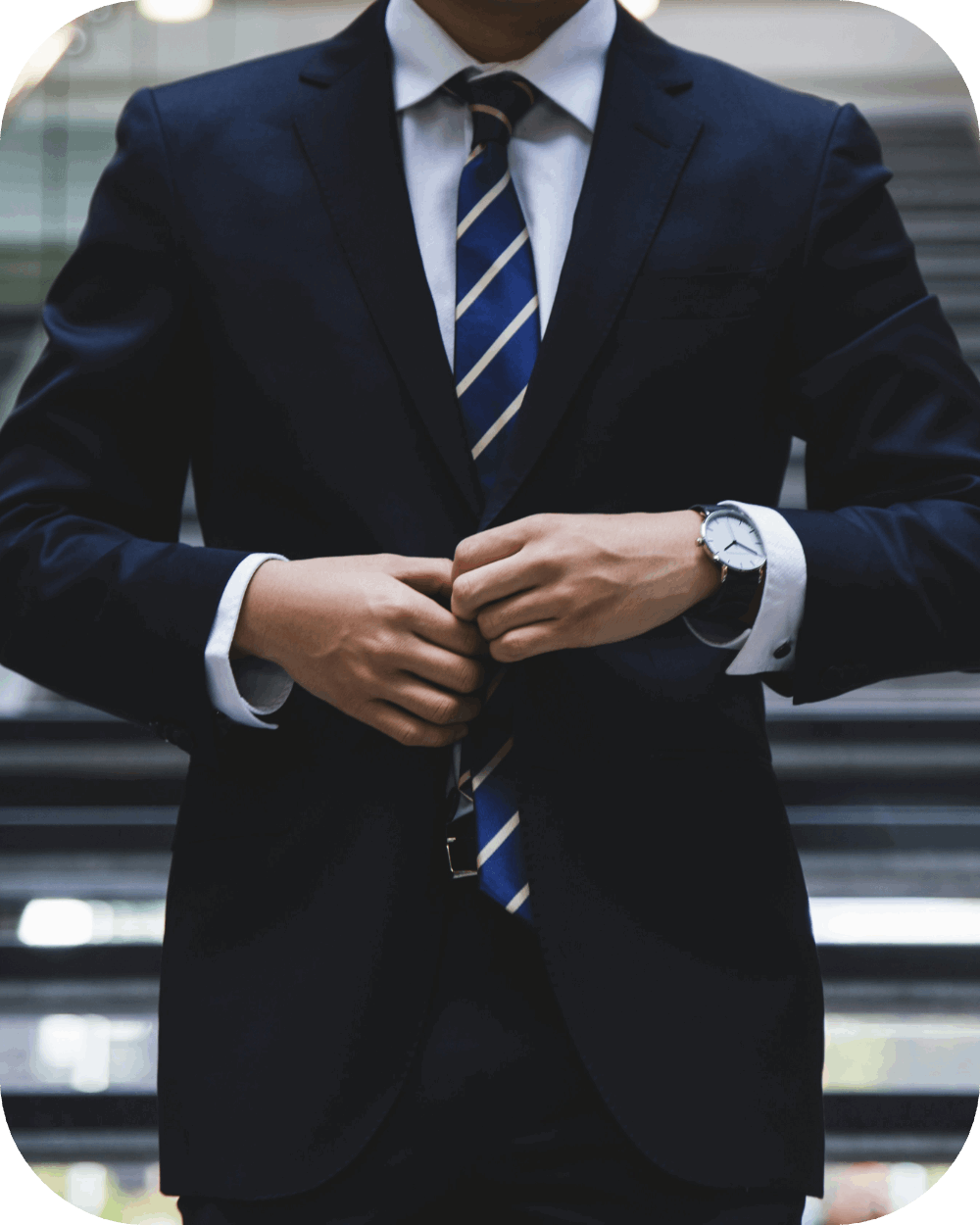 A man in a business suit buttoning up his suit jacket.