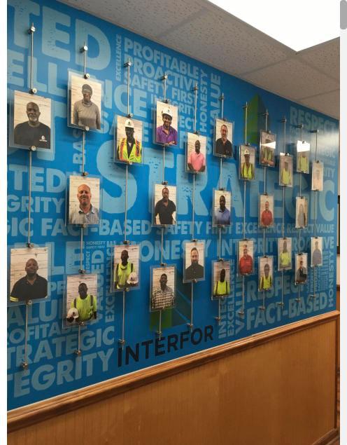 Employee photo panels mounted on a blue word-pattern wall graphic