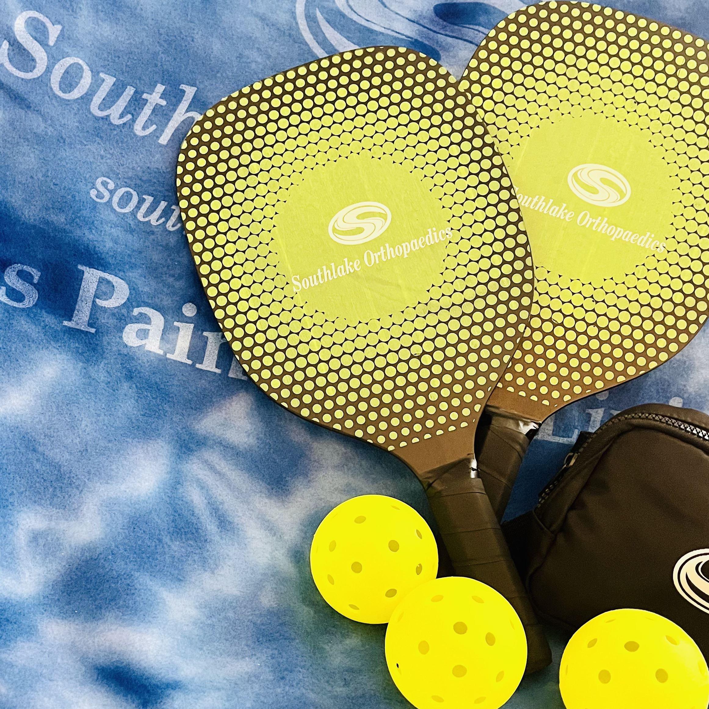 Custom Southlake Orthopaedics pickleball paddles with yellow pickleballs