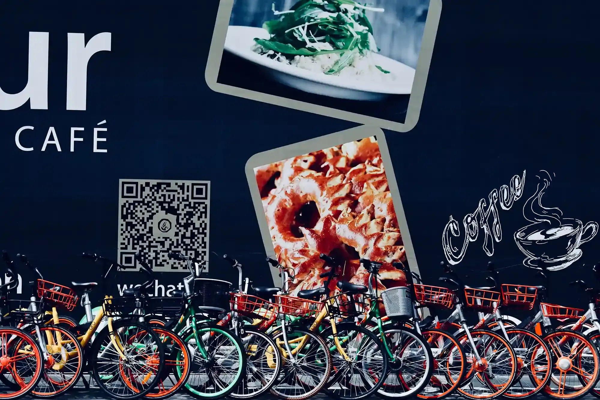 An image of the side of a building with bikes on front of it. The building has advertising for a business and a QR code on it.