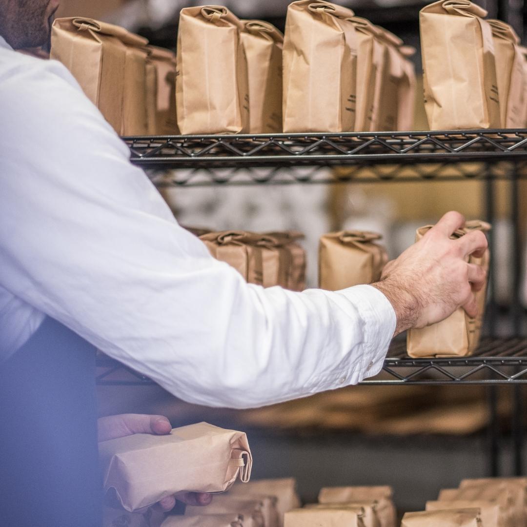 man picking coffee bags off a shelf