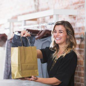 A woman smiling working the register at a boutique