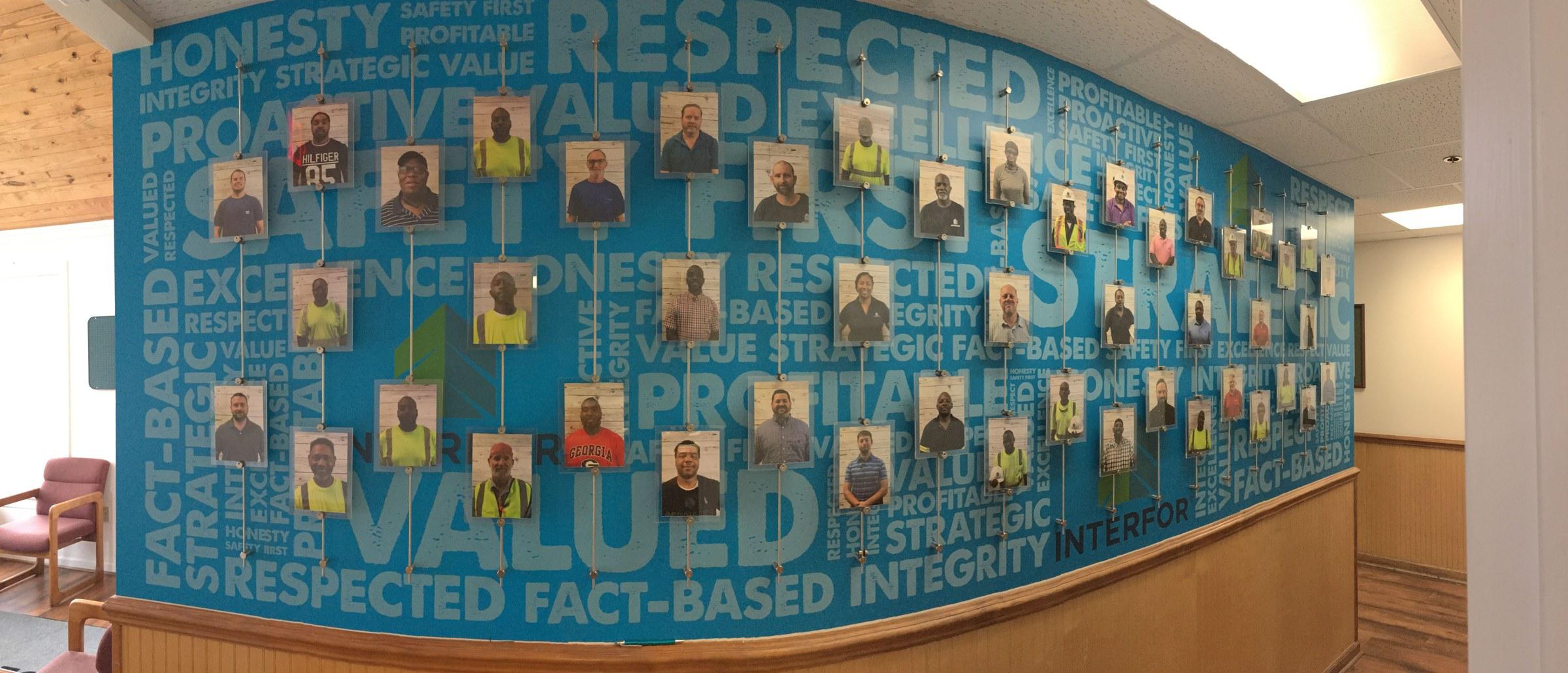 Blue word-pattern wall mural with employee photo panels