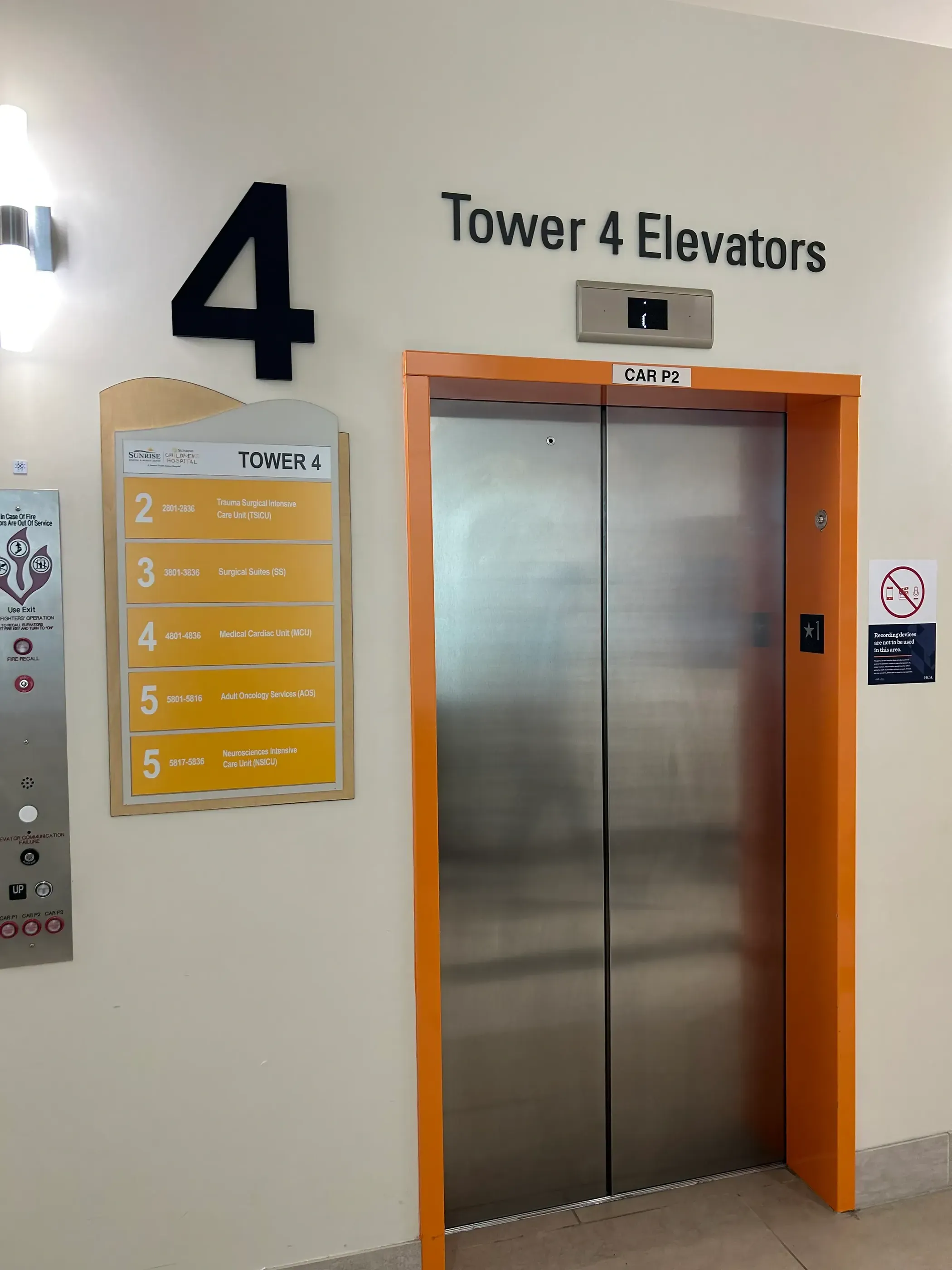Tower 4 elevator at Sunrise Hospital with clear wayfinding signage, including a large number ‘4’ and a directory listing floors and their corresponding departments. The elevator is framed with an orange outline, enhancing visibility.