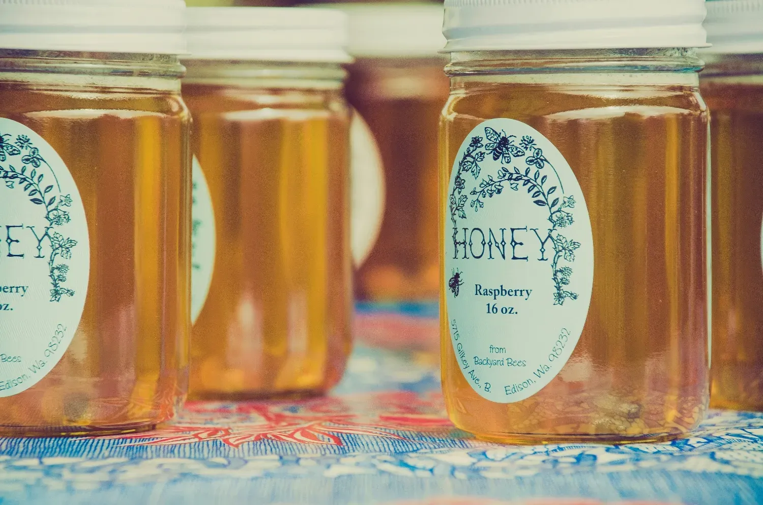 A photo of a jar of honey at a farmer's market with a sticker label.