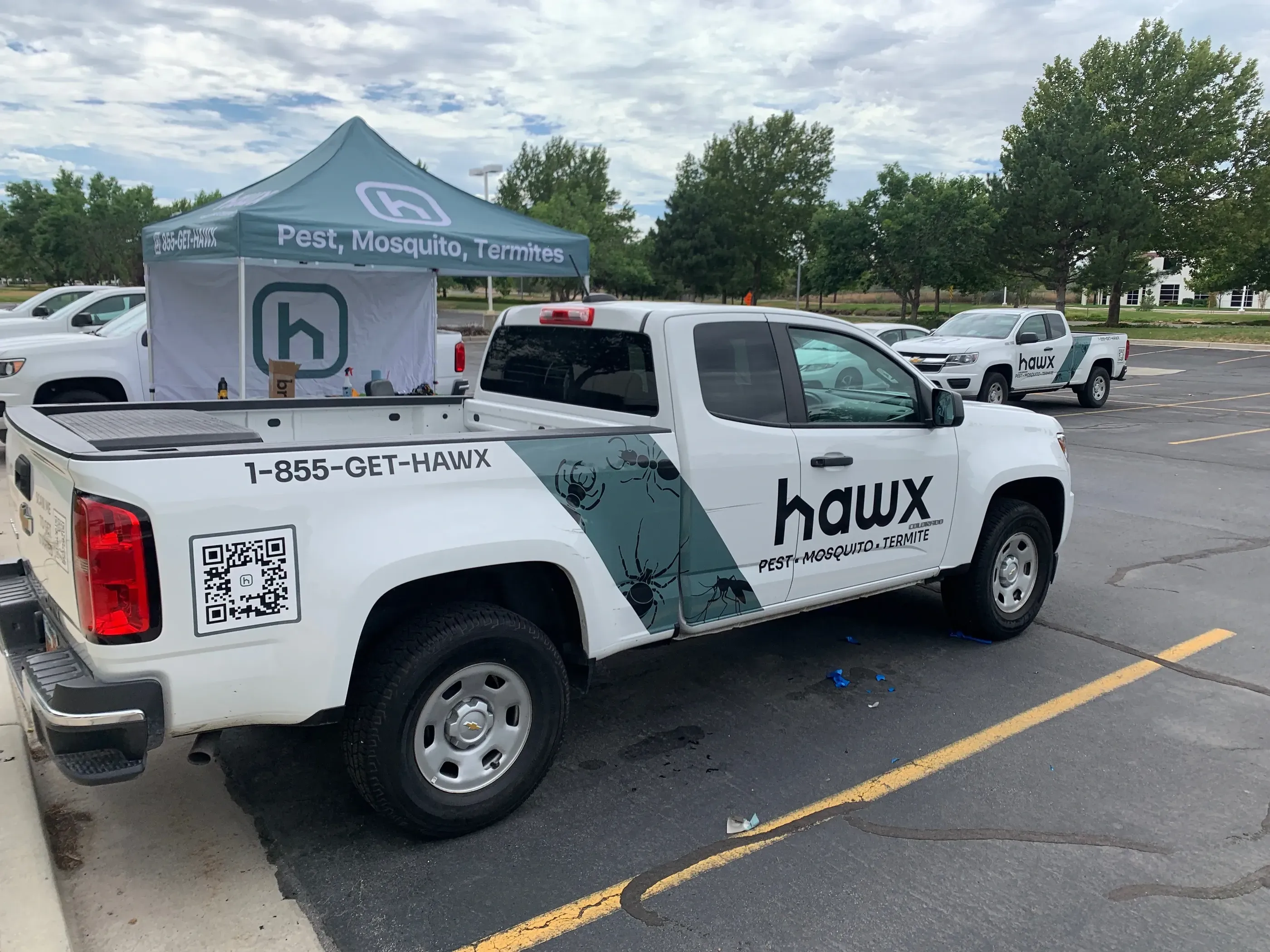 Hawx Pest Control pickup with logo, QR code, and insect graphic.